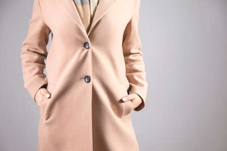 woman with hand in pocket coat on gray background
