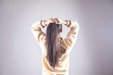 young woman to tie hair on gray backgroundの写真素材