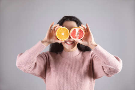 happy woman holding orage and grapefruit in eye