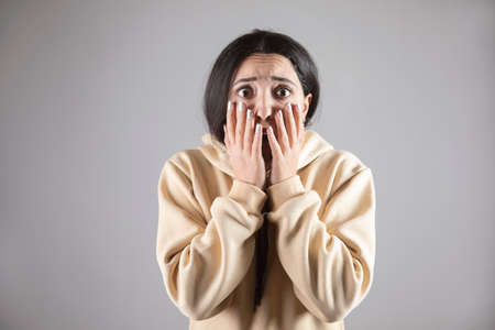 young scared woman on gray wall backgroundの写真素材