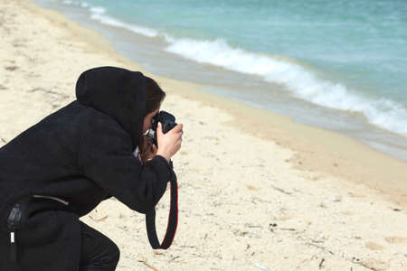 Photographer holding a camera on the beachの写真素材