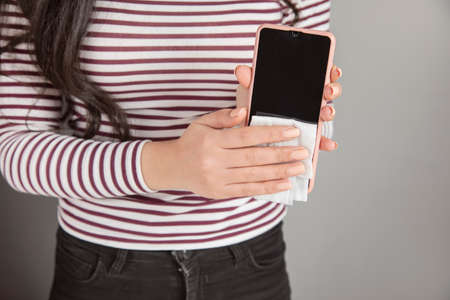 Woman cleaning mobile phone with antiseptic wipe