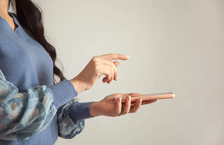 young woman holding smart phone on gray backgroundの写真素材