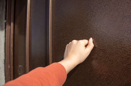woman knock on the brown house doorの写真素材