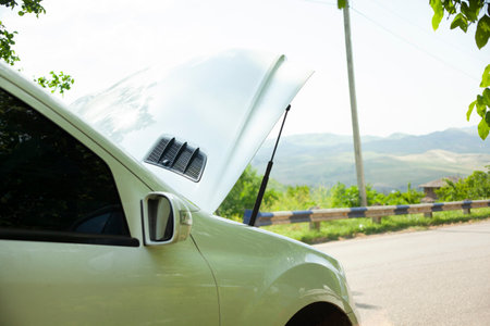 car with open hood on a roadの写真素材