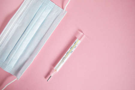 mask and thermometer on pink tableの写真素材