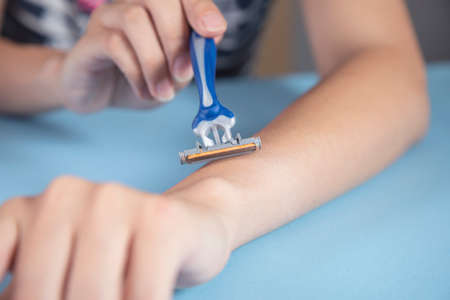 woman holding razor on the blue table