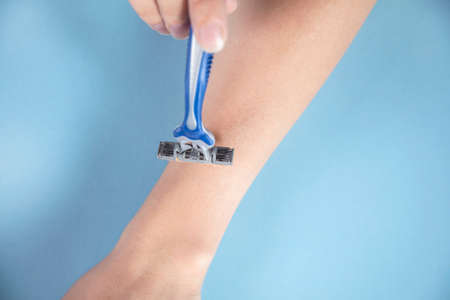 woman holding razor on the blue tableの写真素材