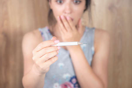 the surprised and sad woman holding thermometerの写真素材
