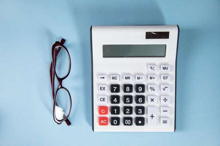 Glasses with calculator on the table.
