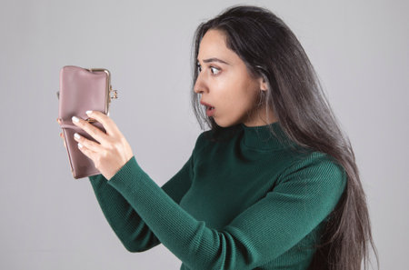 sad and surprised woman holding and looking empty walletの写真素材