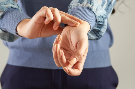 Female hand checking pulse on gray background