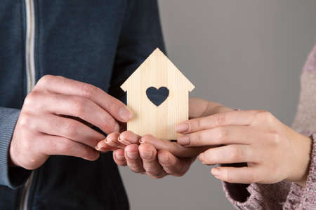 woman and man holding wooden house modelの写真素材