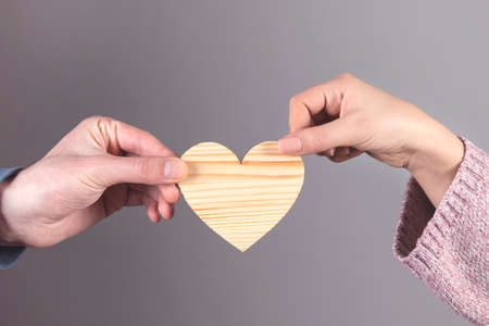 young man and woman holding wooden heartの写真素材