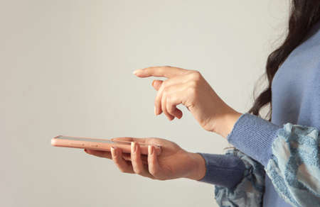 young woman holding smart phone on gray backgroundの写真素材