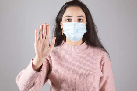 young woman face medical mask and hand stop signの写真素材