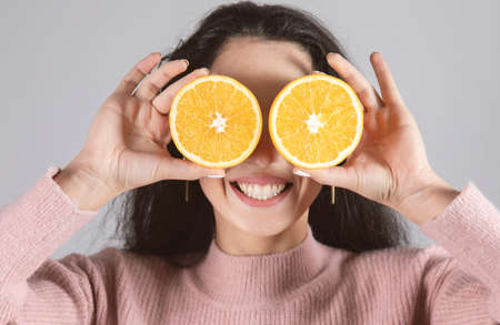 young happy woman holding orage in eyeの写真素材