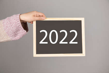 young woman holding blackboard or chalkboard with 2022 textの写真素材