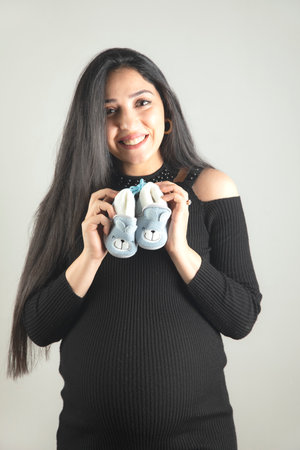 young pregnant woman hand baby shoes