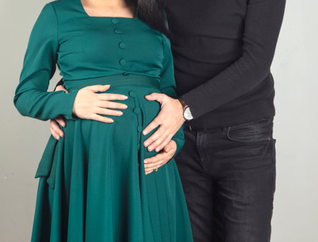 beautiful pregnant woman and her handsome husband hugging bellyの写真素材