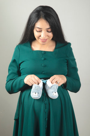 young pregnant woman hand baby shoesの写真素材