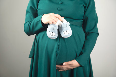 young pregnant woman hand baby shoesの写真素材