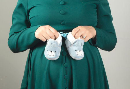young pregnant woman hand baby shoesの写真素材