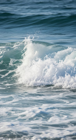 A close-up captures a wave cresting and breaking, showcasing the turquoise water and the explosion of white foam. The ocean's power is evident in the dynamic movement and texture.の素材