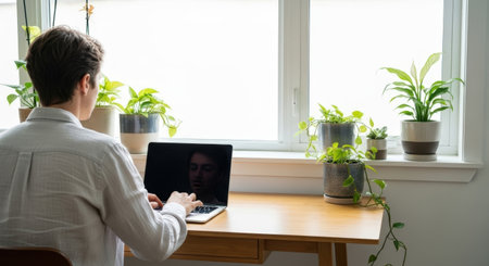Back view of young businessman using laptop computer while sitting at desk in officeの素材