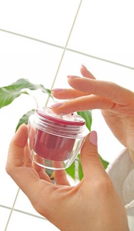 Female hands with a cosmetic cream on the white backgroundの写真素材