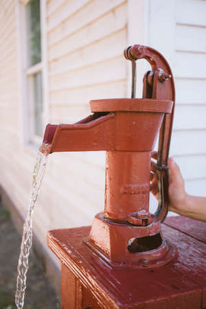 Child using an old red water pumpの写真素材