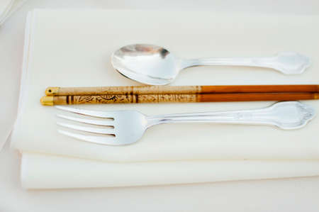 Silver fork and spoon with chopstick on a napkinの写真素材