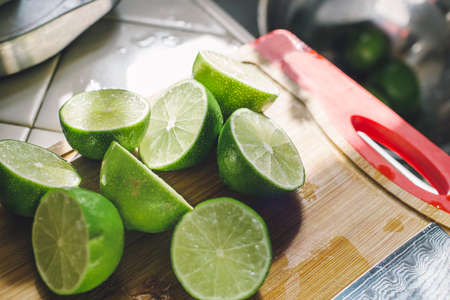 A bunch of cut green limes on a wood chopping board