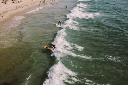 High view of surfers and swimmers in the ocean on a sunny day