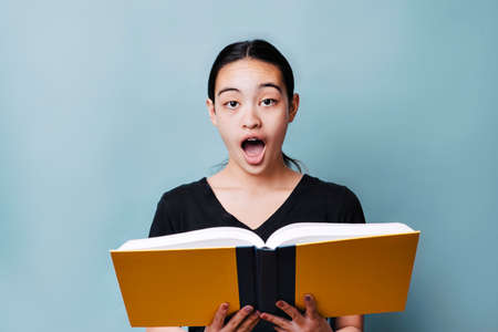 Young female teenager is excited about reading a bookの写真素材