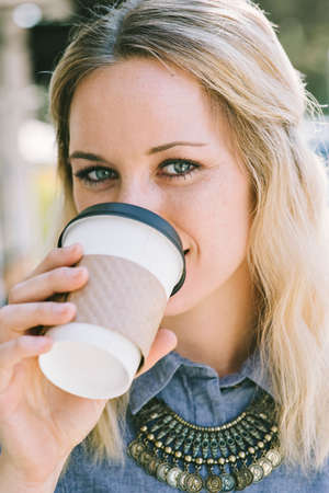 Young white millennial female sips a cup of coffee