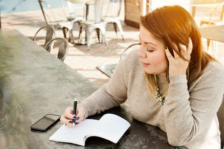 A young woman writes her 2019 New Years Resolutions in a journal