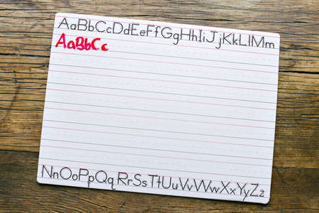 Top view of a white penmanship board with the letters ABC written in red marker by a childの写真素材