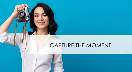 Portrait of a beautiful young woman in white shirt holding camera and looking at camera isolated over blue backgroundの素材