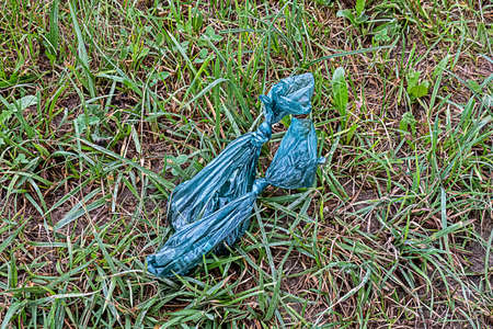 Dog waste bags thoughtlessly disposed of on meadowの写真素材