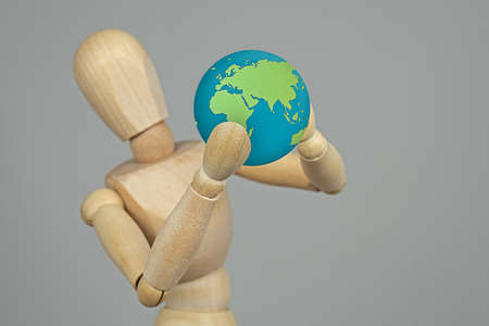 Wooden doll holding the earth in its hands