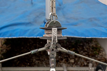 close up of a winch and bracket on a sailing ship, boat covered with a blue  tarpaulin over the...
