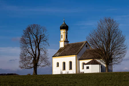 beautiful church framed by two leafless treesの写真素材