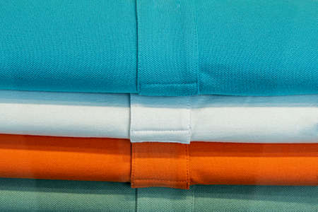 blue, white, orange and green colored shirts in a heapの写真素材