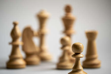 different chess pieces out of focus in the background, only one pawn in focus in the foregroundの写真素材