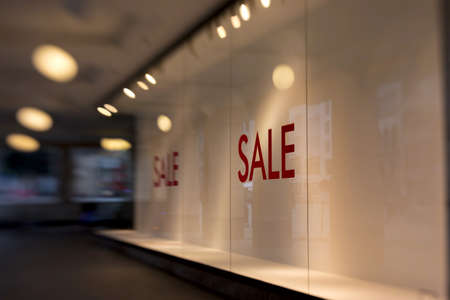 sale written in red letters on the on the pane of an empty shop window