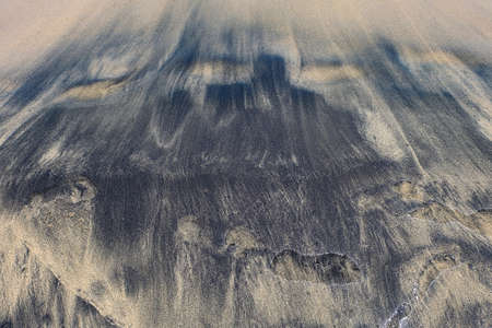 texture, background of beige black sand with small puddles of waterの写真素材