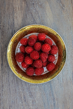 fresh raspberries in a white in a gold-plated porcelain bowl