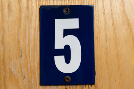 old blue enamel sign with white number 5 on a wooden wallの写真素材