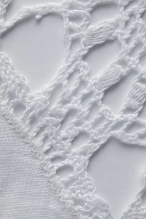 extreme close up of a crocheted lace against white background